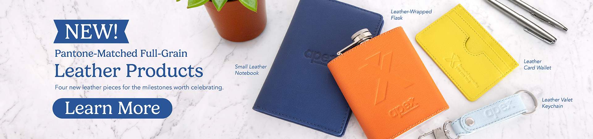 Flat-lay of branded leather merchandise — notebooks, flasks, card wallets and keychains in full color